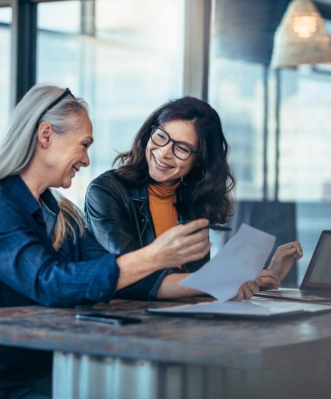 two marketers smile at each other as they review results